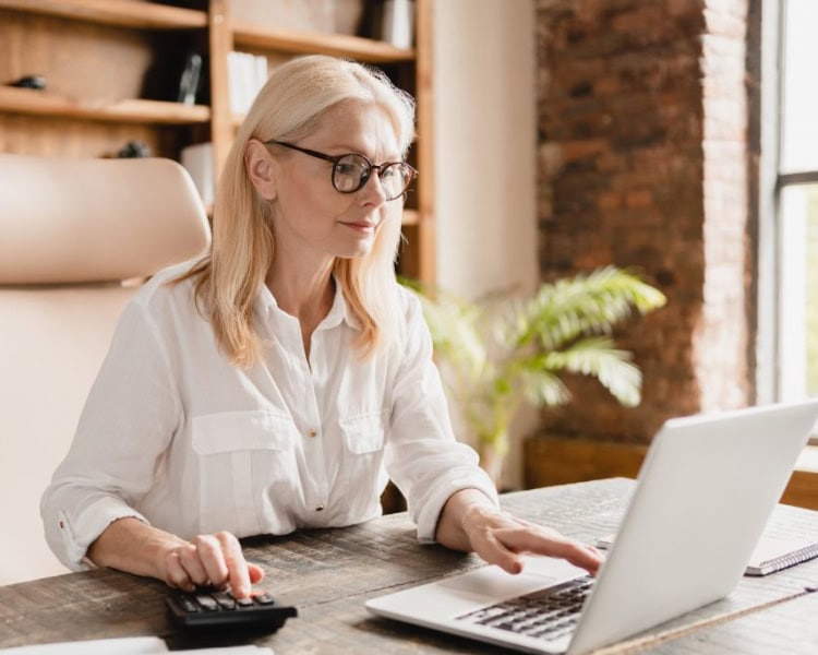 shutterstock_2083529695 (1) Woman using a calculator and working on a laptop