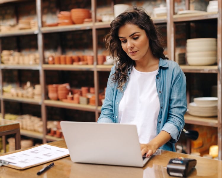 Young,Ceramic,Shop,Owner,Using,A,Laptop,While,Working,In self employed woman on laptop