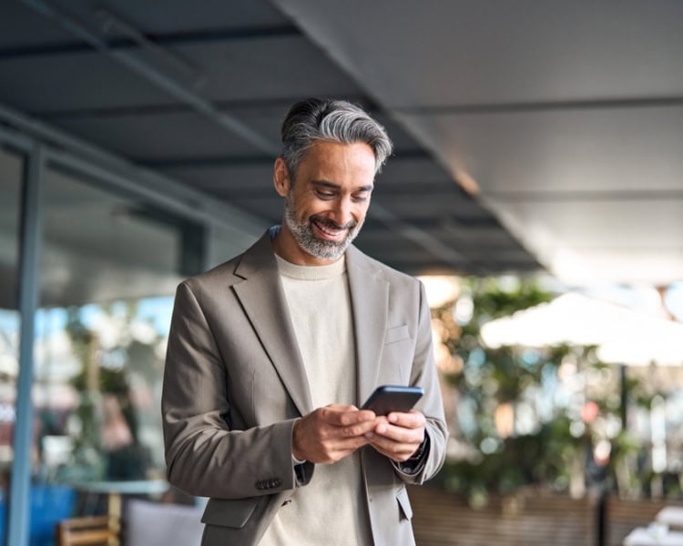 Happy,Mature,Older,Male,Entrepreneur,Standing,Outdoors,Looking,At,Smartphone. senior executive on his phone smiling